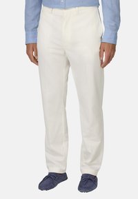 Pantaloni in lino bianchi con un design a gamba dritta, caratterizzati da una parte davanti piatta e tasche anteriori, abbinati a mocassini in suede blu.