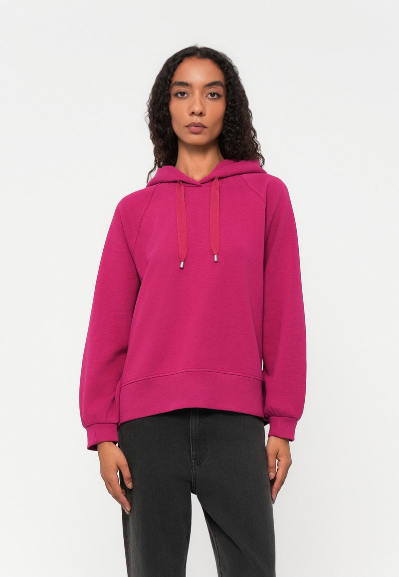 Fuchsia Kapuzenpullover mit Kordelzug, gerippten Bündchen und Saum. Bequeme Passform und glatte Textur. Kombiniert mit dunklen Jeans.