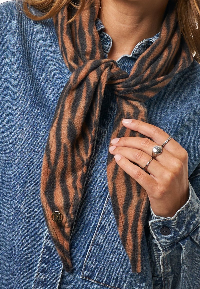 Braun und schwarz gestreifter Schal aus weichem Stoff, zu einem Knoten gebunden, getragen mit einer Jeansjacke. Verfügt über einen goldenen Hardware-Akzent.