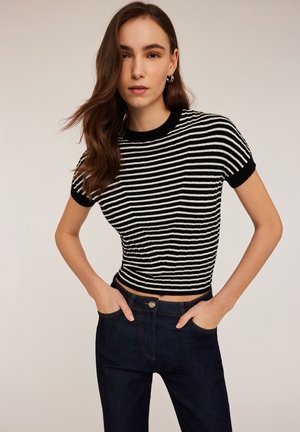 Schwarz-weißer gestreifter, kurz geschnittener T-Shirt mit kurzen Ärmeln und geripptem Material. Kombiniert mit dunklen Jeans aus Denim mit Knopfverschluss.