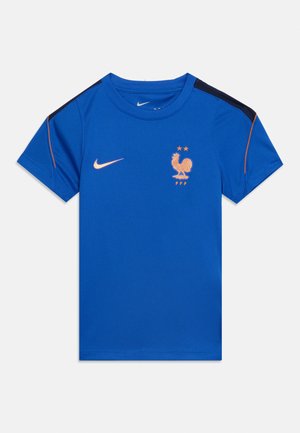 Modra športna majica s kratkimi rokavi in oranžnim logotipom Nike na desnem prsnem delu, grb petelina Francoske nogometne zveze z dvema zvezdicama na levem prsnem delu.