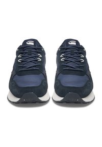 Tumši zili sporta apavi ar zamšādas un tekstila materiālu kombināciju, kur ir auklu aizdare, balti akcenti un teksturēta gumijas zole.