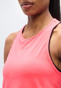 Ροζ αθλητική μπλούζα χωρίς μανίκια με στρογγυλή λαιμόκοψη. Διαθέτει υφασμάτινη υφή με διακριτική λεπτομέρεια λογότυπου στο μπροστινό μέρος.