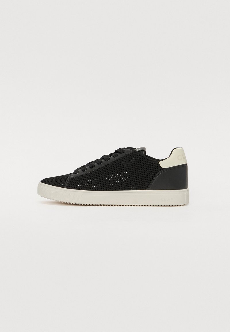 Black mesh sneakers feature a smooth black leather heel and tongue, white rubber sole, and black laces. Subtle branding near the heel.