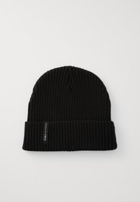 Bonnet en tricot côtelé noir avec un revers et une petite étiquette en tissu noir sur le côté. Texture douce, forme cylindrique.