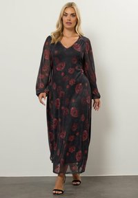 Vestido largo floral en tejido transparente, con mangas largas, escote en V y un fondo oscuro con un patrón de rosas rojas.