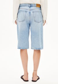 Vaaleansiniset farkkushortsit, rento istuvuus, näkyvät tikkaukset, kaksi takataskua ja nahkainen merkkilappu vyötäröllä.