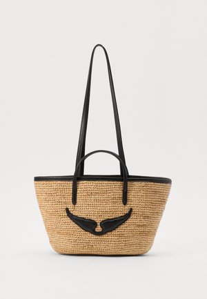 Sac cabas en paille tressée avec finition en cuir noir, deux longues anses, deux courtes anses et un motif noir en forme d’aile sur le devant.