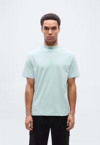 Πρά σινο μέντας κοντομάνικο T-shirt με ψηλό γιακά και μαύρο λογότυπο "BOSS" στο λαιμό. Λείο βαμβακερό ύφασμα, κανονική εφαρμογή, απλός σχεδιασμός.