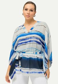 Blusa a righe blu con scollatura a V, design fluido, tessuto morbido e trasparente, cinturino regolabile in vita e linee nere di accento.