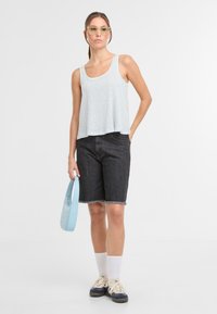 Lyseblå og hvidstribet top, sorte denimshorts med udfransen kant, klare briller, lyseblå taske, hvide crew-sokker og sneakers.