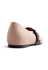 Shoe flat in suede beige con punta affilata e dettaglio della cinturino nero. La scarpa presenta una suola bassa nera e una texture liscia.
