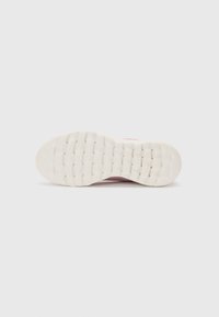 Shoe sole with a textured white rubber surface and rounded pattern. Features a light pink upper section, blending into the sole.