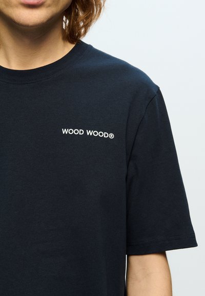Marineblå bomulds-t-shirt med rund hals og korte ærmer, med "WOOD WOOD®" logo i hvidt på venstre brystområde.