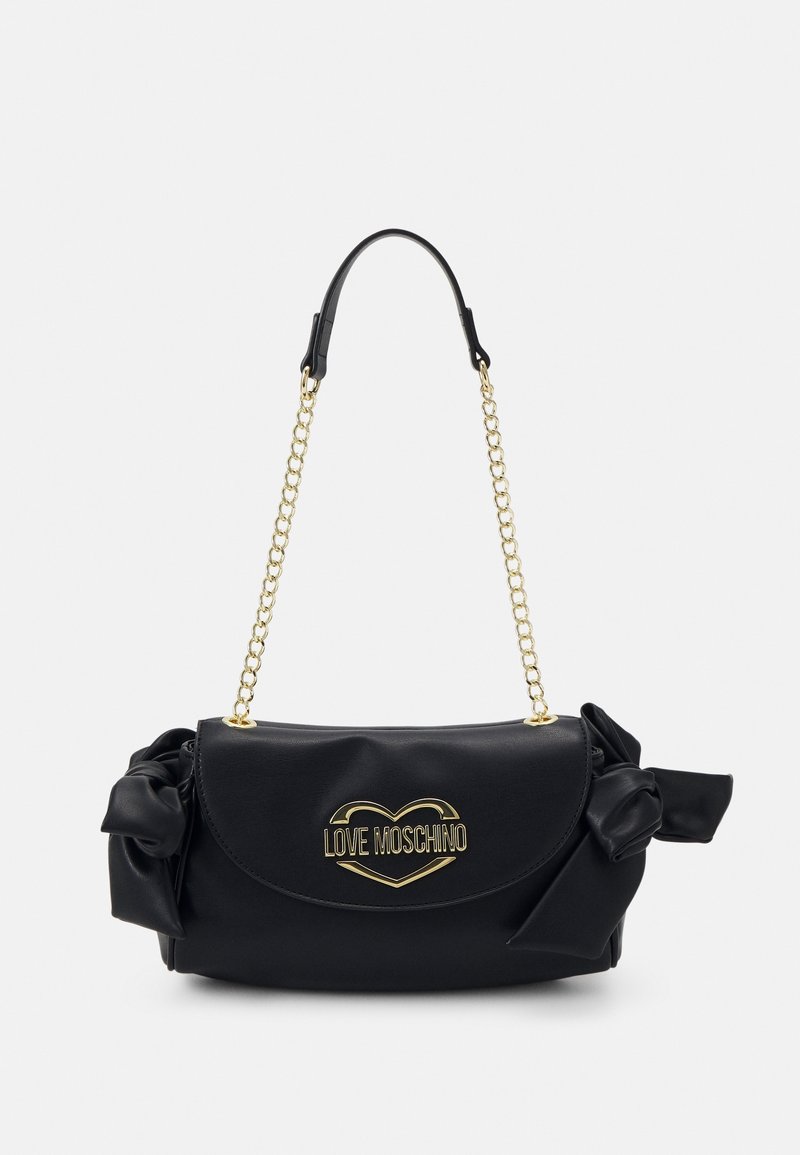 Sac à main en similicuir noir avec une anse chaîne, un nœud décoratif et un logo cœur doré "LOVE MOSCHINO" sur le devant. Texture lisse avec fermeture à rabat.