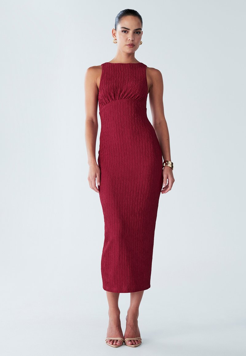 Burgundy midi-mekko, jossa on teksturoitu kangas, olkaimeton muotoilu, rypytetty vyötärö ja istuva siluetti, yhdistettynä beigen värisiin hihna-korkokenkiin.
