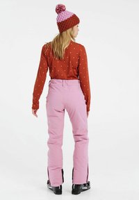 Dámsky outfit s hnedou dlhou polka-dot blúzkou s dlhým rukávom, ružovými snehovými nohavicami so zipsami a dvojfarebnou pletenou čiapkou s pom-pomom.