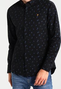 Camicia nera con bottoni, caratterizzata da un motivo astratto blu e un logo arancione. Realizzata in tessuto morbido, con maniche lunghe e colletto classico.