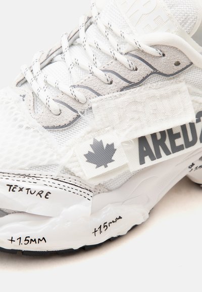 Gros plan d'une basket blanche avec mesh, accents en suède, lacets à motifs, texte "PARED", logo de feuille d'érable, et "+1.5MM" et "TEXTURE" manuscrits sur la semelle.