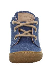 Blauwe denim enkelboot met beige veters en een tan suède patch. Beschikt over een geprofileerde rubberen zool en contrasterende stiksels langs de randen.