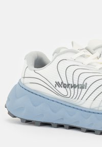 Weiße Laufschuhe mit einer strukturierten Oberfläche, grauen Akzenten und einer blauen, robusten Sohle mit Zick-Zack-Mustern für besseren Halt.