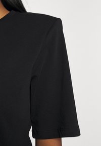 Svart kortärmad t-shirt i mjuk bomull, med rundad halsringning och subtil ribbad struktur, med rena sömnadsdetaljer.