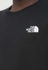 Μαύρο βαμβακερό T-shirt με στρογγυλή λαιμόκοψη. Διαθέτει λευκό κεντημένο λογότυπο "The North Face" στην αριστερή πάνω πλευρά. Μαλακή υφή.