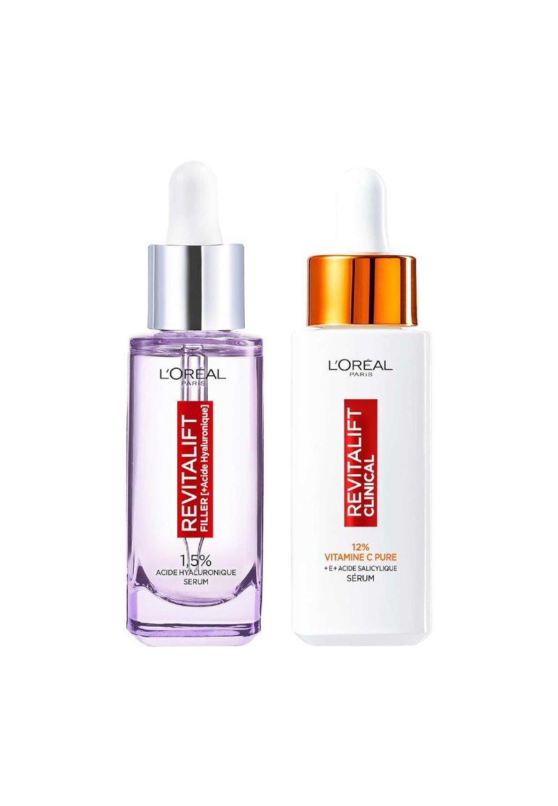 Sérums L'Oréal dans des flacons en verre transparent : à gauche, teinte violette avec un compte-gouttes argenté ; à droite, blanc avec un capuchon doré, tous deux étiquetés.