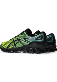 Scarpe da corsa Asics con una tomaia nera e verde neon caratterizzata da un motivo a onde, un'imbottitura GEL prominente e una suola modellata.