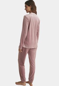 Velvet loungewear set in zachte roze. Langmouwtop en broek met elastische tailleband en afgeknipte pijpen. Soepele textuur; ontspannen pasvorm.