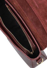 Bordeaux leren handtas met een gladde textuur, voorzien van een enkele ritscompartiment gevoerd met zwarte stof en gouden metalen accenten.