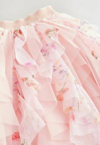 Rosa Tüllrock mit gestuften Rüschendetails, einem glitzernden Taillenbund und floralen Mustern in Pastellfarben. Weicher Stoff mit dezentem Glanz.