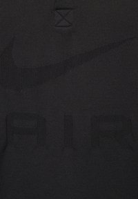 Maglietta nera a maglia con un evidente logo "NIKE" e la scritta "AIR" in rilievo. Design minimalista senza colori o motivi aggiuntivi.