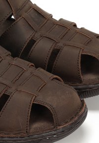 Sandalias de cuero marrón con diseño de punta abierta, upper tejido, superficie texturada y suela de goma resistente.