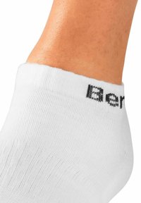 Calza ankle bianca realizzata in un tessuto liscio e elasticizzato con polsino a costine. Il nome del marchio "Berk" è stampato in nero sul polsino.