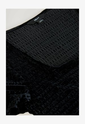 Musthave, tekstuuriga pehme kangast top mustas toonis, millel on volditud muster. Omab ümmargust kaelust ning näitab brändi sildit "NEXT" krael.