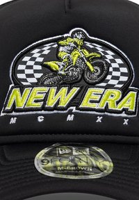 Μαύρο καπέλο μπέιζμπολ με κεντημένο σχέδιο μοτοσικλετιστή σε κίτρινο και λευκό, με το κείμενο «NEW ERA» σε έντονα γράμματα από πάνω. Περιλαμβάνει ρυθμιζόμενο λουράκι.