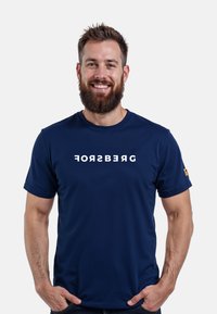 Camiseta de cuello redondo azul marino hecha de una tela suave, con la palabra "FORSBERG" en letras blancas en negrita en el pecho. Pequeño logo en la manga.