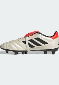 Botas de fútbol plateadas con franjas negras y acentos rojos. Presentan un empeine de cuero texturizado, un frente con cordones y una suela exterior de goma moldeada.