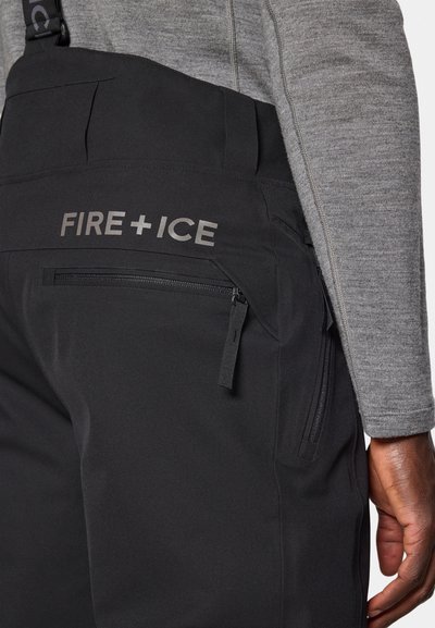 Μαύρο παντελόνι με τιράντες και λεία υφή, με πλαϊνή τσέπη με φερμουάρ και εμφανές λογότυπο "FIRE+ICE" σε γκρι στο πίσω μέρος.