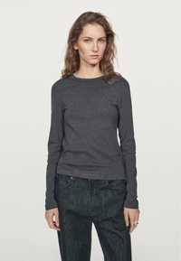 Dark gray long-sleeve fitted top with a round neckline, made of soft fabric, paired with dark denim high-waisted pants.