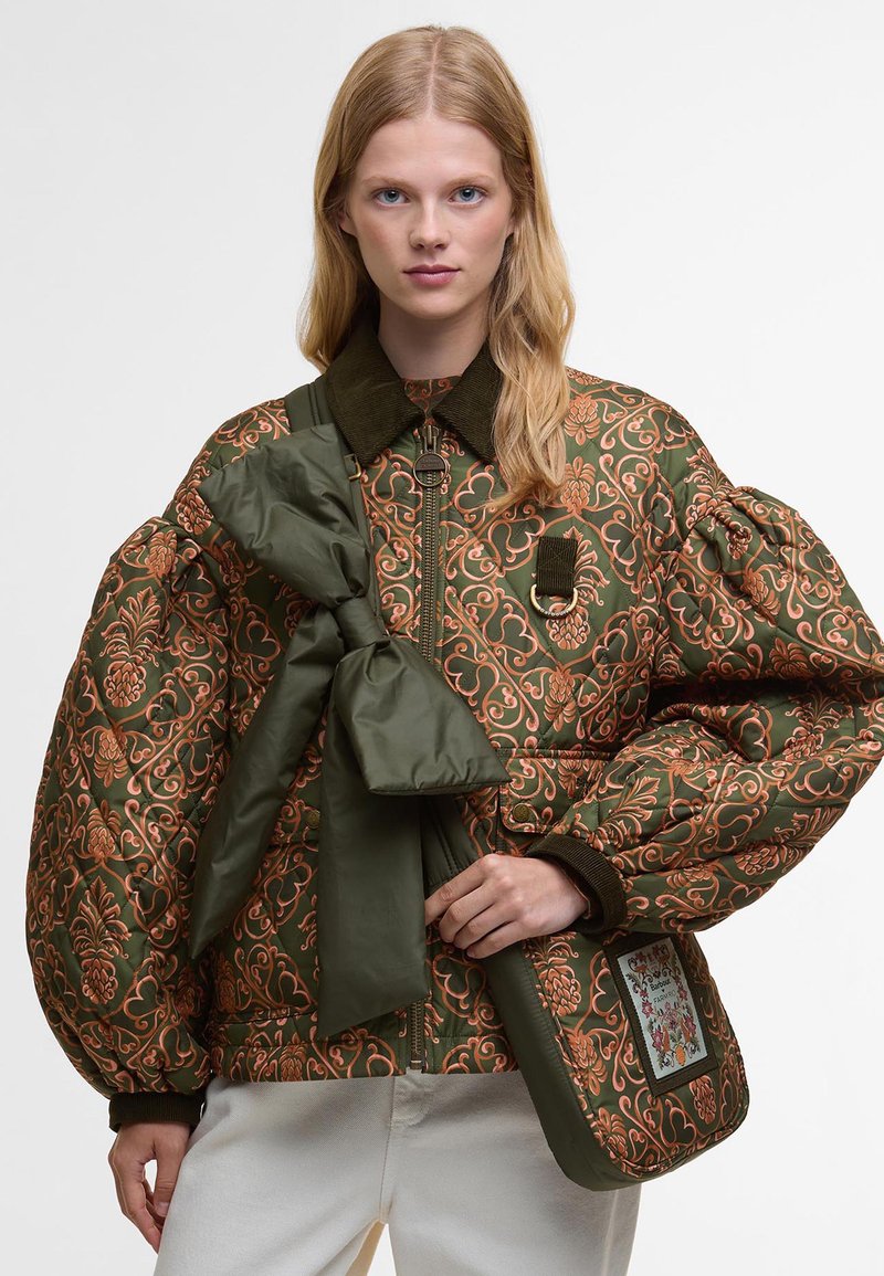 Puffowana zielona kurtka z miedzianymi haftami kwiatowymi, wyrazistym kołnierzem i dużymi rękawami. W zestawie znajduje się zielona kokarda i torebka.
