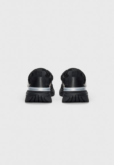 Schwarze Sportschuhe mit einem eleganten Design, featuring ein strukturiertes Obermaterial, einem silbernen Akzent und einer dicken Gummisohle.