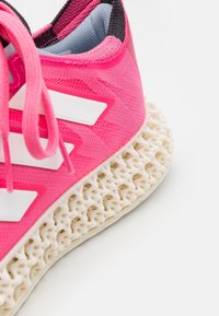 Baskets de sport roses avec tige en mesh, logo à trois bandes blanches et semelle intermédiaire blanche texturée conçue pour le soutien et l'amorti.