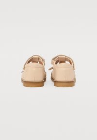 Sandales en cuir tan avec un dos ouvert, dotées de deux sangles ajustables et d'une semelle en caoutchouc avec une surface texturée.