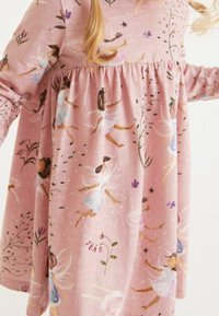 Rosa klänning i mjukt tyg med en fantasifull fe-tryck, långa ärmar och en rynkad midja med blommiga detaljer.