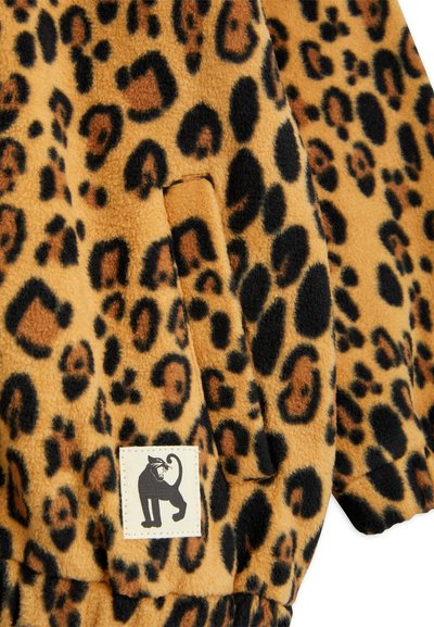 Tessuto in pile con stampa leopardata in diverse sfumature di marrone e nero; presenta una tasca laterale e un’etichetta con il profilo di un gatto nero.
