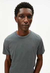 Graues Baumwoll-T-Shirt mit Rundhalsausschnitt, kurzen Ärmeln und einem kleinen gestickten Logo auf der Brust; glatte Textur und lässige Passform.