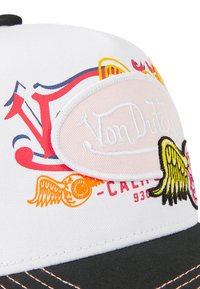 Casquette de baseball blanche avec des motifs brodés colorés, y compris des ailes et un patch logo. Visière noire avec des détails de couture contrastés.