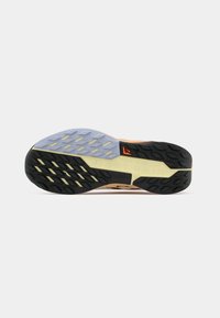 Semelle de chaussure de sport noire et orange avec des motifs texturés contrastés, comprenant une section lisse bleu clair et des accents jaunes, conçue pour l'adhérence.